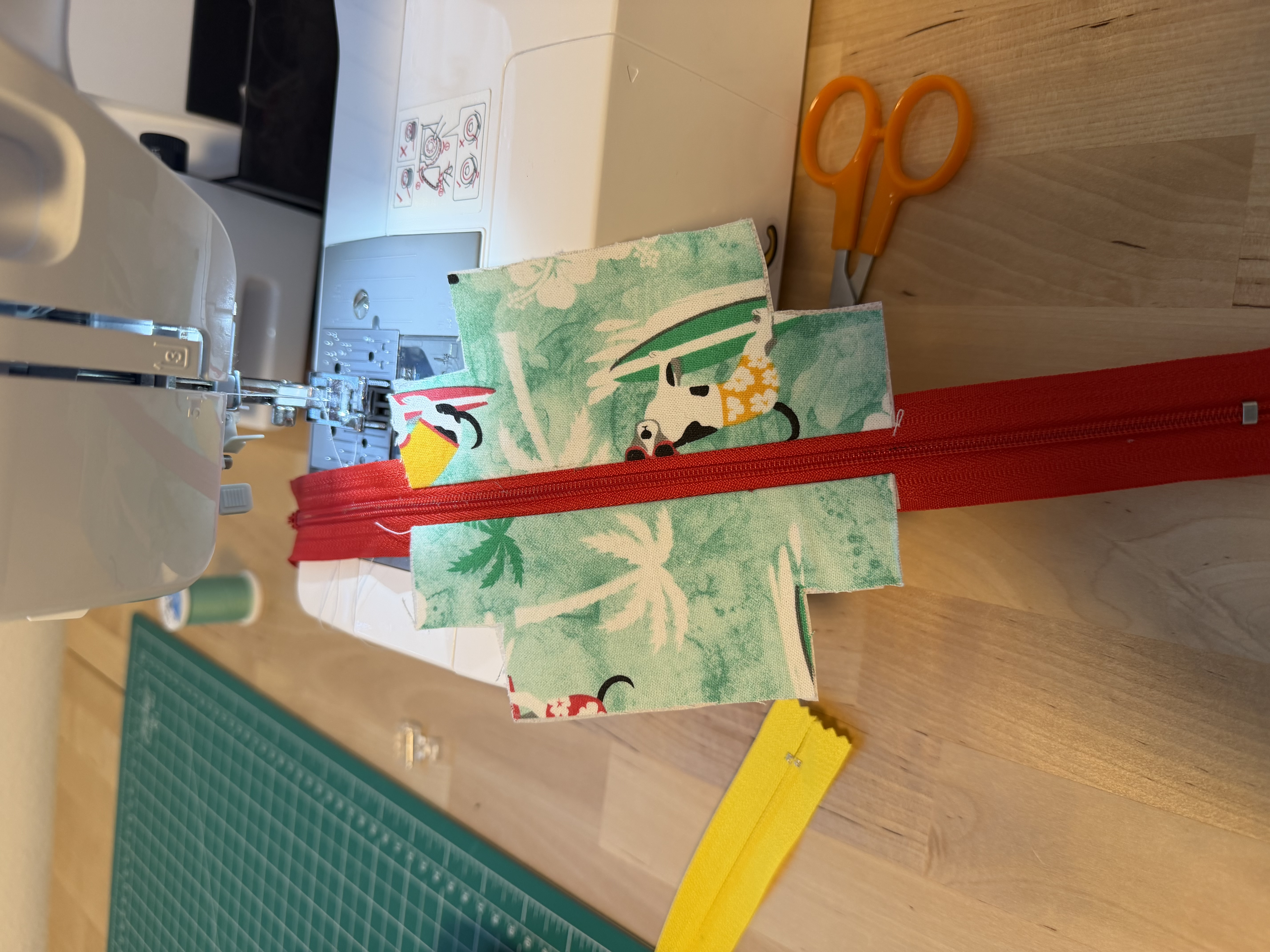 Sewing the red zipper onto the tropical surfing dogs print fabric at the sewing machine