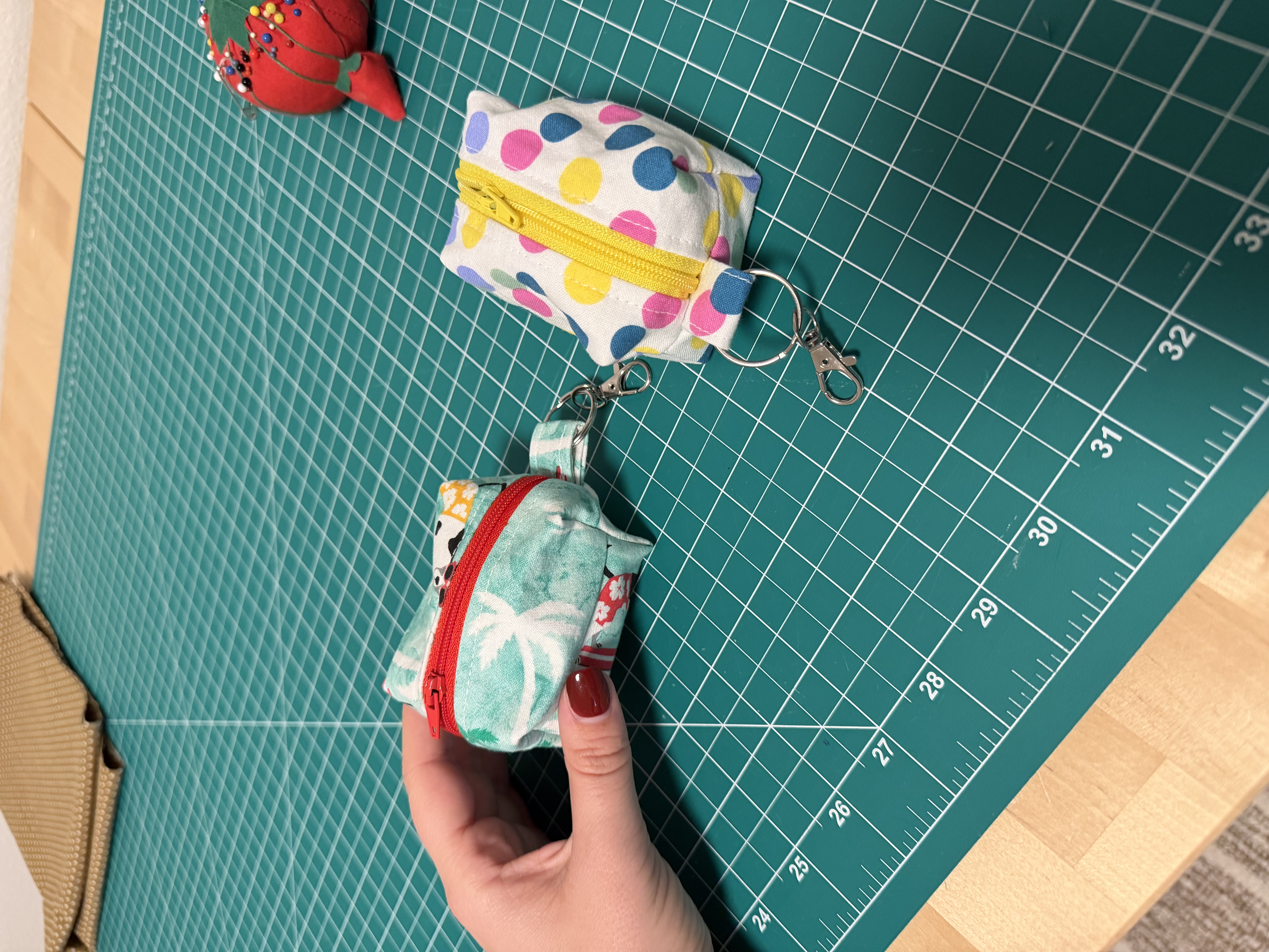The two finished dog poop bag holders, a polka dot pouch and a tropical surfing dogs print pouch