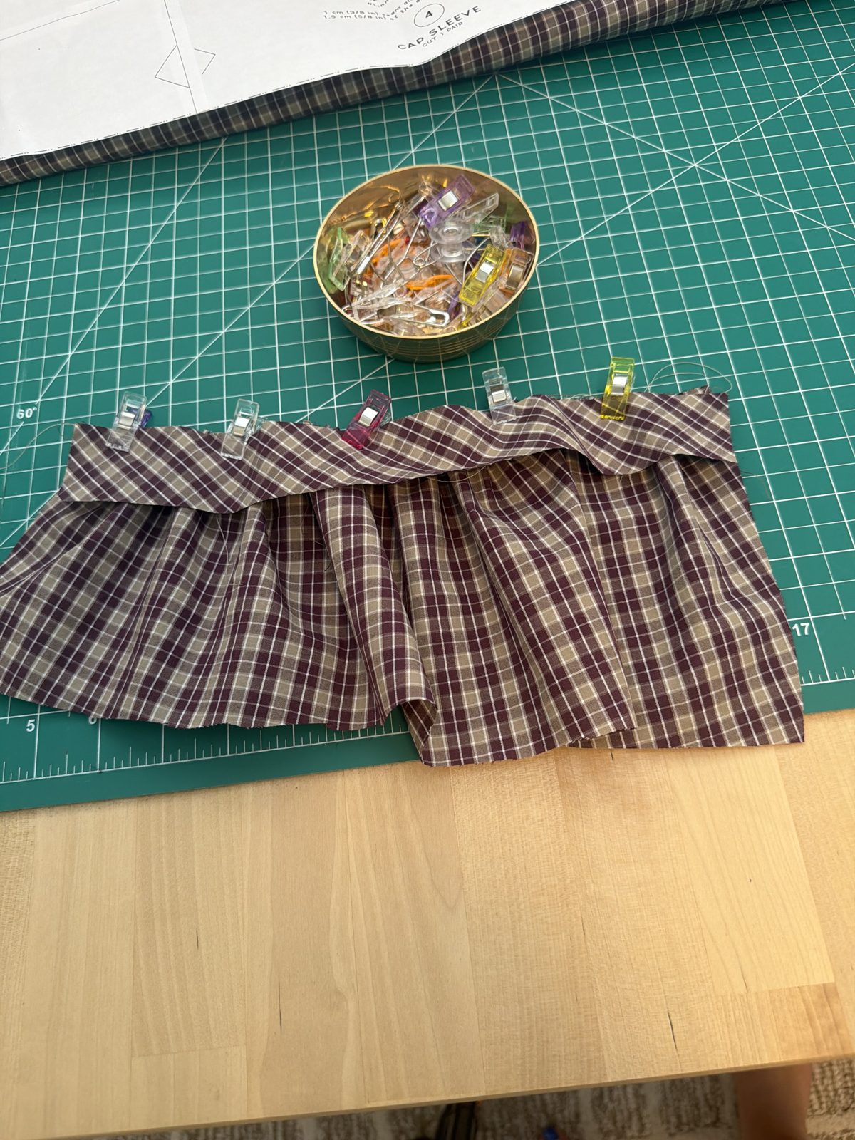 A gathered cap sleeve piece held with sewing clips on the cutting mat