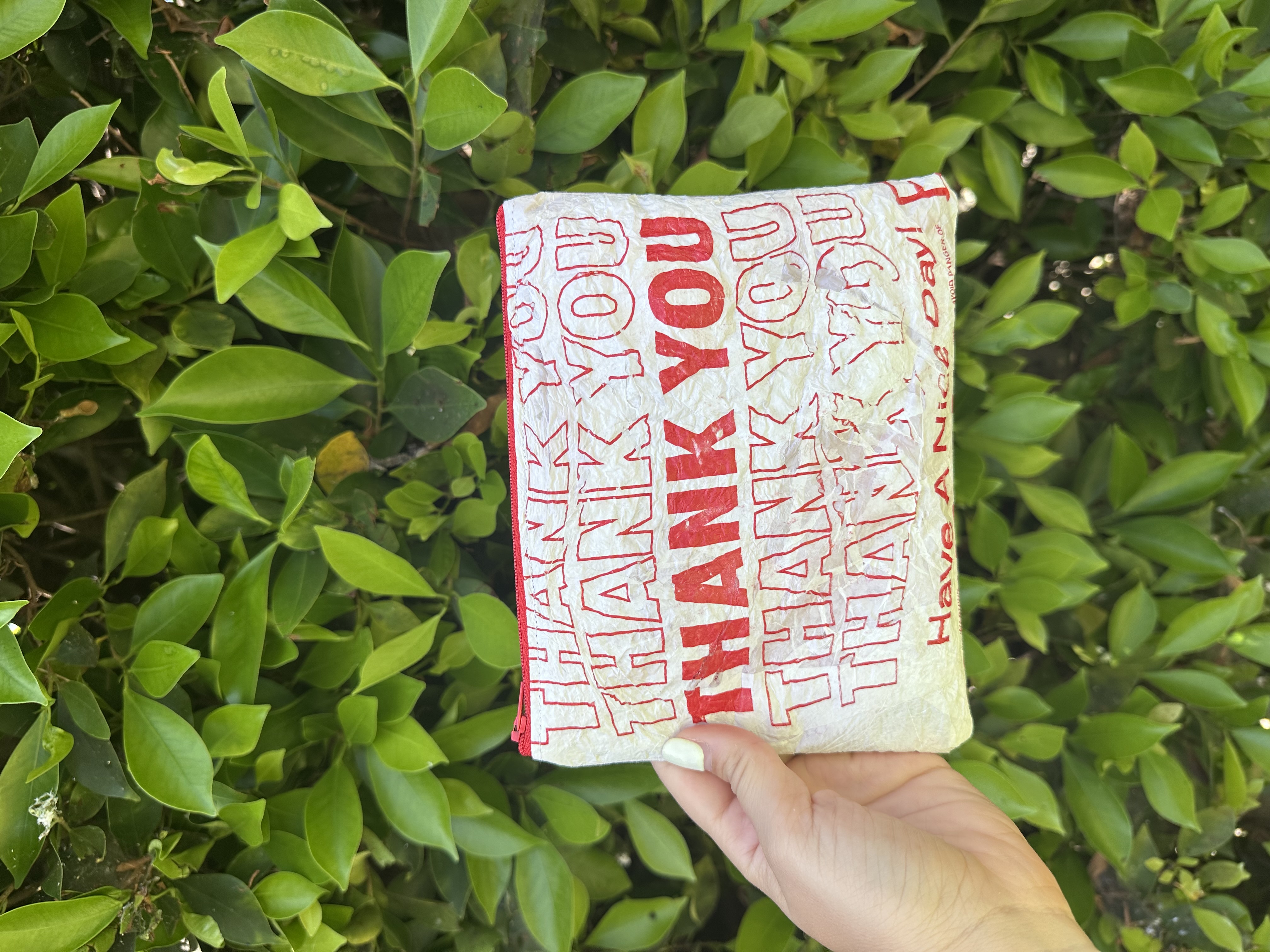 A finished upcycled zipper pouch made from a fused 'thank you' takeout bag